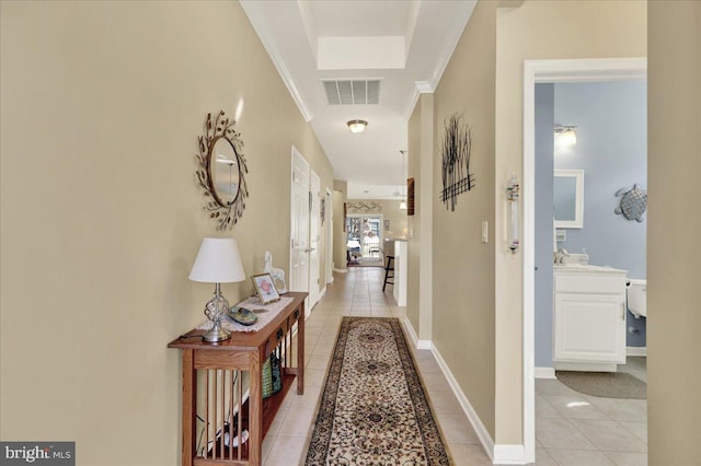 hallway featuring crown molding, light tile patterned floors, baseboards, and visible vents