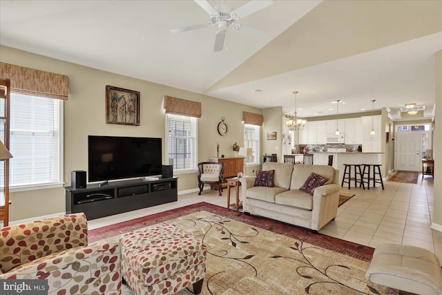 living room with light tile patterned floors, ceiling fan with notable chandelier, baseboards, and lofted ceiling