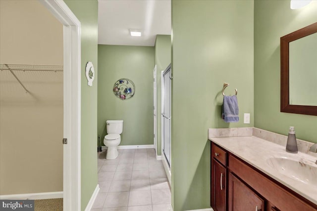 bathroom featuring vanity, baseboards, a stall shower, tile patterned floors, and toilet