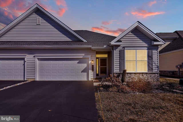 view of front of property with stone siding, an attached garage, roof with shingles, and driveway