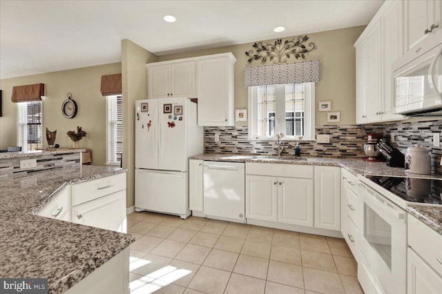 kitchen featuring a wealth of natural light, white appliances, backsplash, and white cabinetry