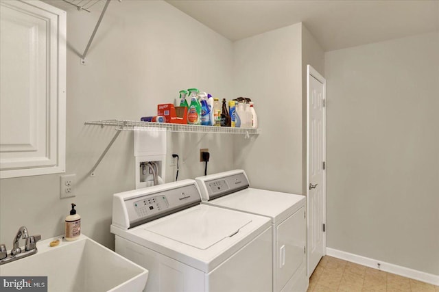 washroom featuring laundry area, independent washer and dryer, baseboards, and a sink