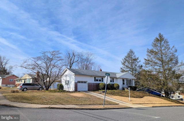 view of front facade featuring a chimney, concrete driveway, a front lawn, a garage, and brick siding