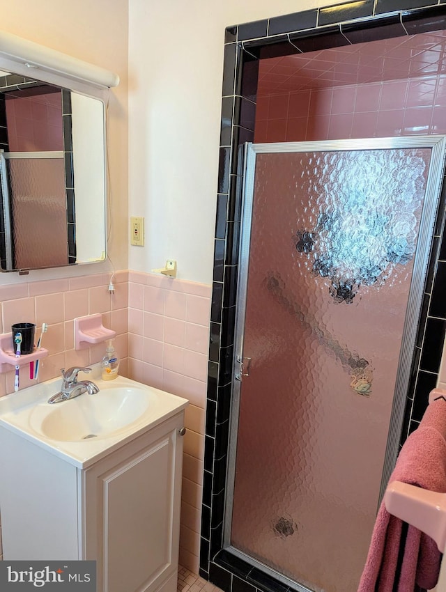 bathroom featuring a wainscoted wall, vanity, tile walls, and a shower stall