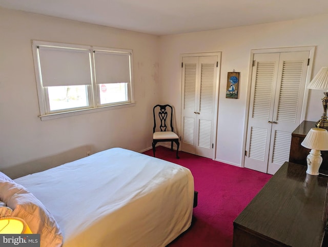 bedroom with dark carpet and two closets