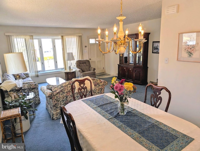 dining area featuring a notable chandelier, visible vents, carpet floors, and a textured ceiling