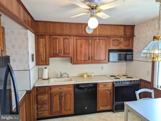 kitchen featuring wallpapered walls, light countertops, brown cabinets, black appliances, and a sink