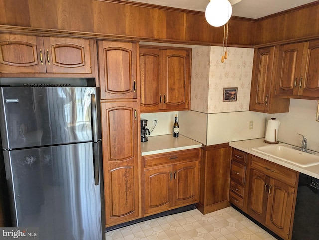 kitchen featuring a sink, dishwasher, light countertops, and freestanding refrigerator