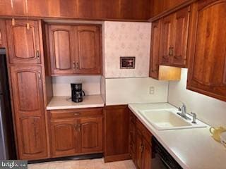 kitchen featuring light countertops, brown cabinetry, and a sink