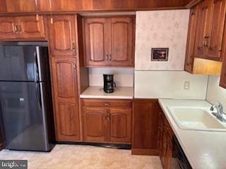 kitchen featuring brown cabinets, light countertops, and freestanding refrigerator