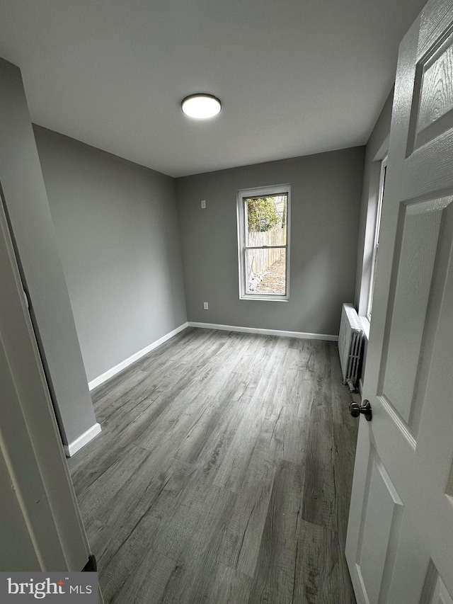 unfurnished bedroom with baseboards, dark wood finished floors, and radiator