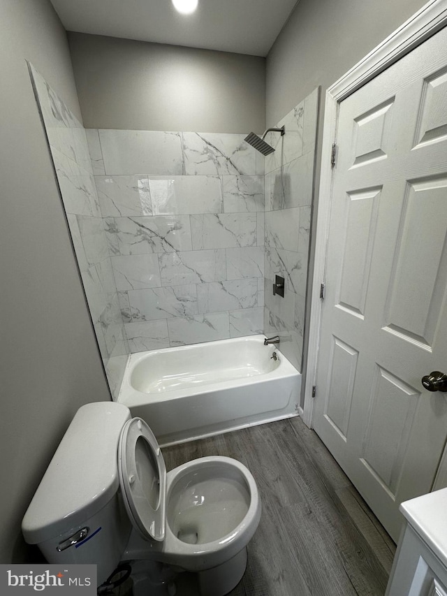 full bath featuring bathtub / shower combination, toilet, and wood finished floors