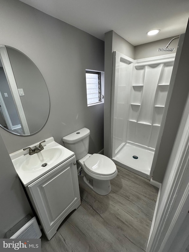 full bath featuring toilet, wood finished floors, vanity, visible vents, and a stall shower