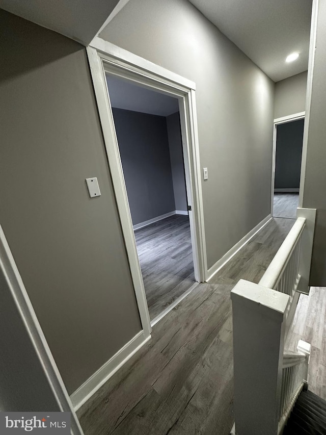 hallway featuring baseboards, an upstairs landing, and wood finished floors