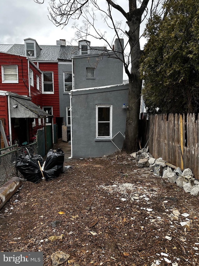 rear view of property with fence, a chimney, and stucco siding