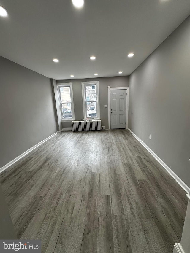 unfurnished room with dark wood-type flooring, recessed lighting, baseboards, and radiator heating unit