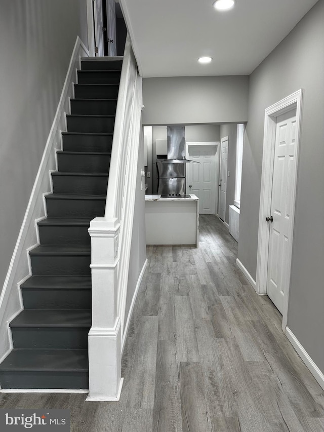 staircase featuring recessed lighting, wood finished floors, and baseboards