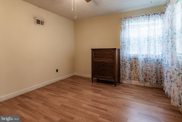 empty room with light wood finished floors, baseboards, and visible vents