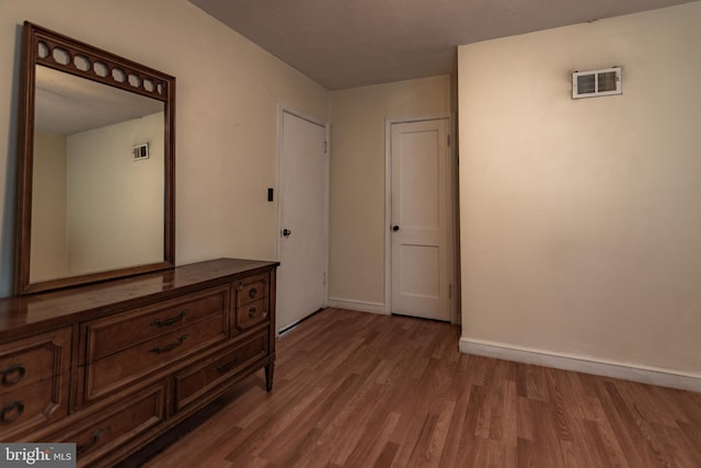 unfurnished bedroom with visible vents, baseboards, and wood finished floors