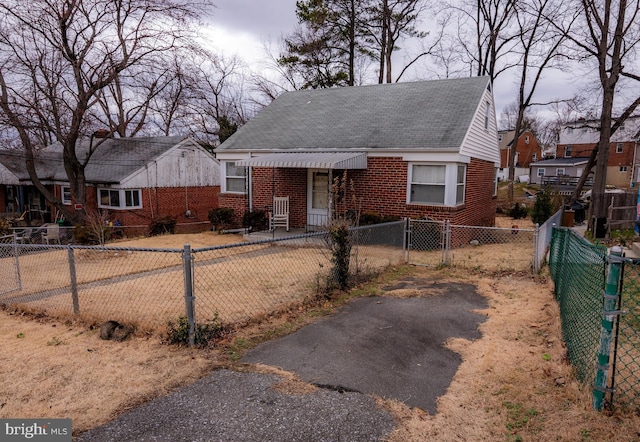 bungalow with a fenced front yard and brick siding