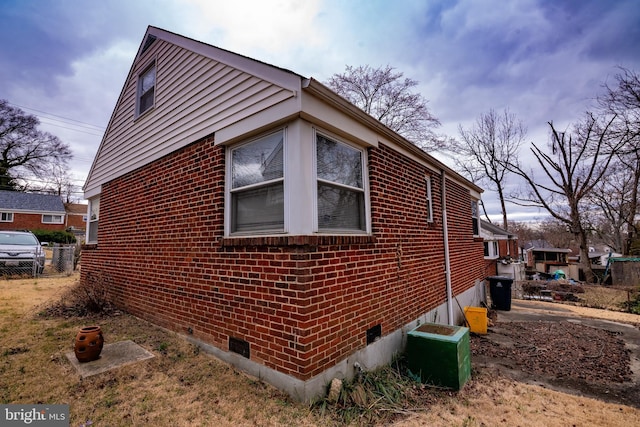 view of side of home with brick siding and fence