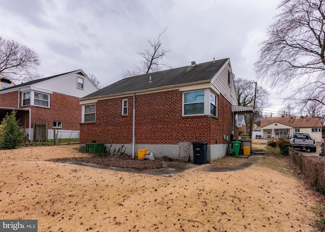 rear view of house featuring brick siding and fence