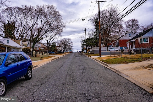 view of street featuring sidewalks, a residential view, curbs, and street lights