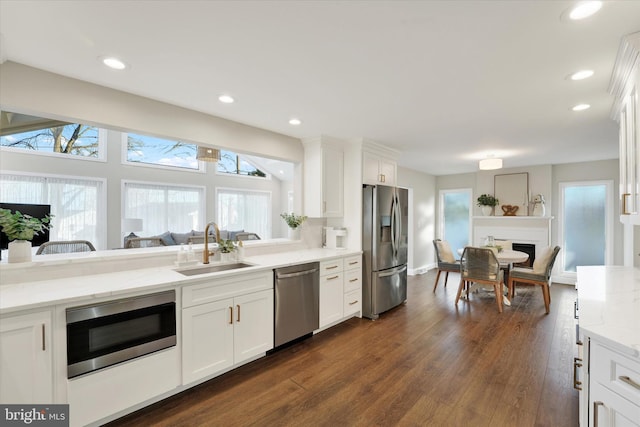 kitchen with a sink, appliances with stainless steel finishes, dark wood finished floors, and a healthy amount of sunlight