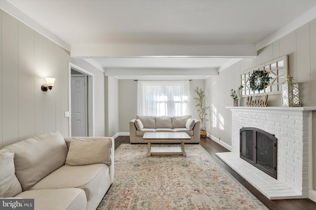 living room featuring baseboards, beam ceiling, wood finished floors, and a fireplace