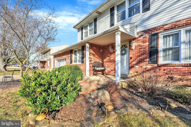 view of exterior entry featuring a garage and brick siding