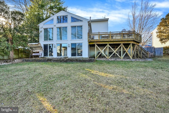 rear view of property featuring stairs, fence, a lawn, and a wooden deck