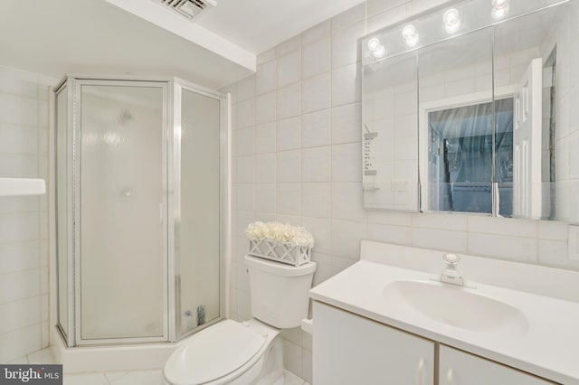 full bath with visible vents, a shower stall, toilet, vanity, and tile walls