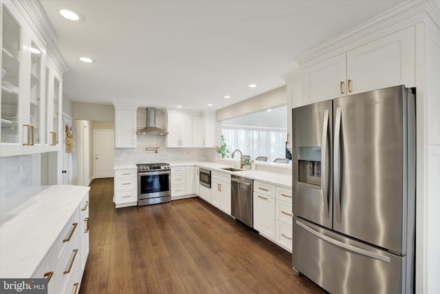 kitchen with white cabinets, wall chimney exhaust hood, appliances with stainless steel finishes, and a sink