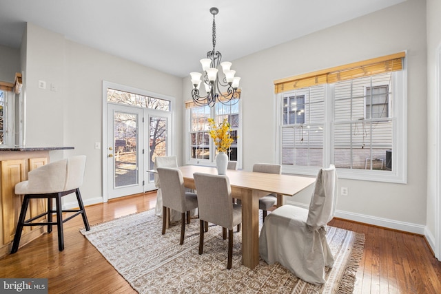 dining area featuring light wood-type flooring, baseboards, and a chandelier