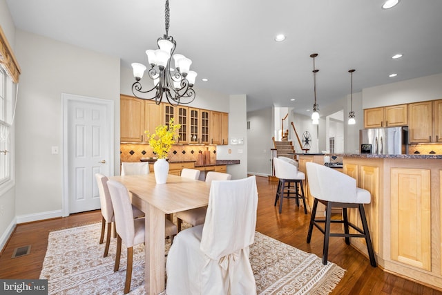 dining area with dark wood-style floors, visible vents, stairway, and an inviting chandelier