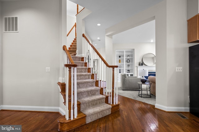 staircase featuring built in shelves, wood-type flooring, visible vents, and baseboards