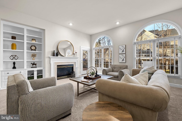 carpeted living room with a premium fireplace, recessed lighting, built in features, and a healthy amount of sunlight