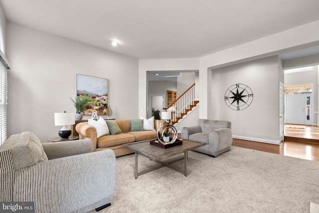 living room featuring baseboards, stairway, and wood finished floors