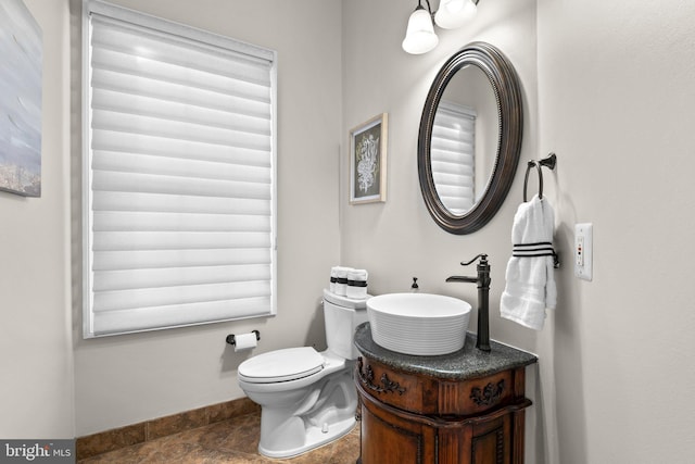 half bathroom featuring baseboards, a sink, toilet, and tile patterned floors