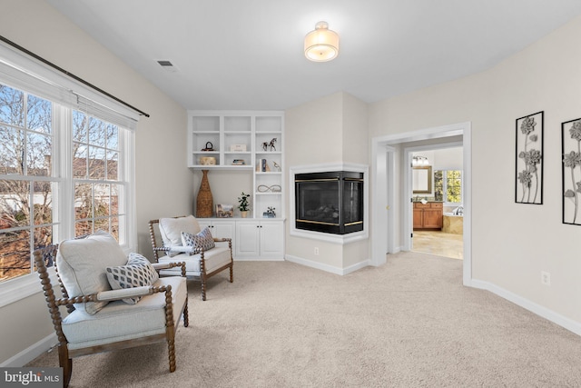 sitting room with light carpet, a wealth of natural light, and baseboards