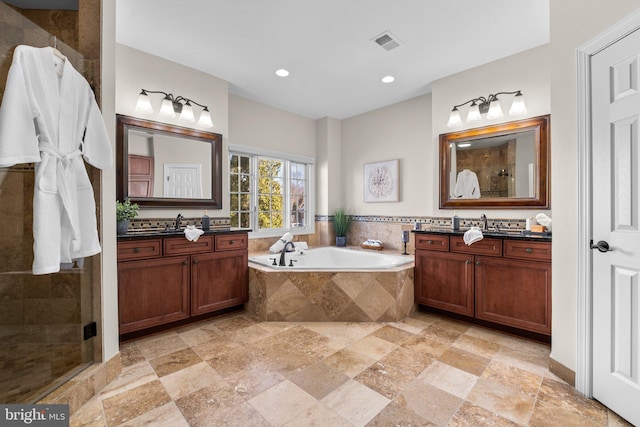 full bathroom with a stall shower, visible vents, a bath, two vanities, and a sink