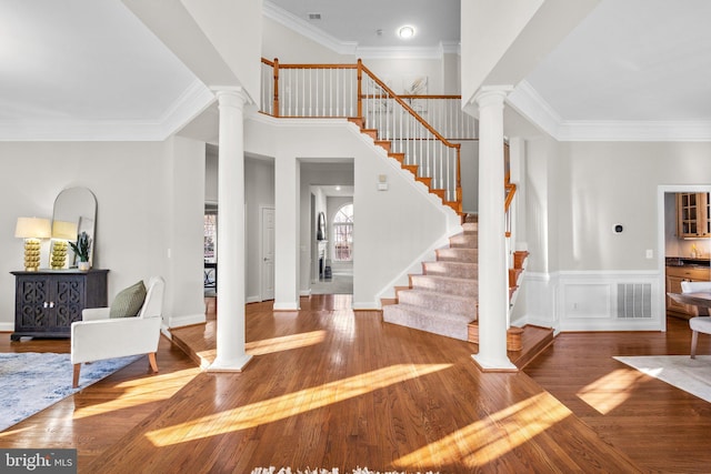 entrance foyer with ornate columns, crown molding, visible vents, and wood finished floors