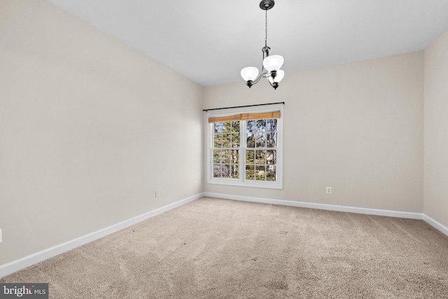 carpeted spare room with a notable chandelier and baseboards