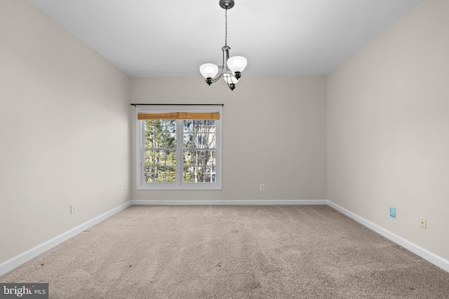 carpeted spare room with baseboards and a notable chandelier