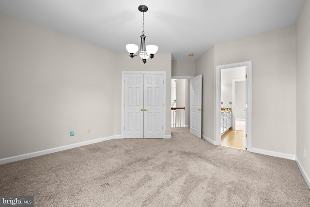 unfurnished bedroom with an inviting chandelier, baseboards, a closet, and light colored carpet