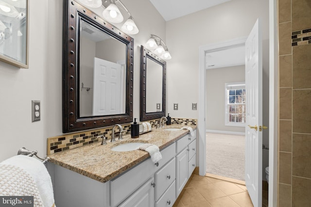 bathroom with tile patterned floors, a sink, decorative backsplash, and double vanity