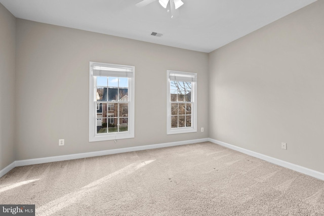 empty room featuring ceiling fan, carpet, visible vents, and baseboards