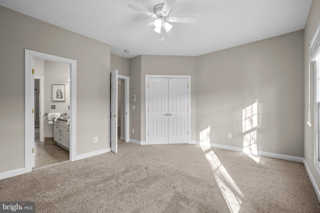 unfurnished bedroom featuring ensuite bath, baseboards, a closet, and light colored carpet