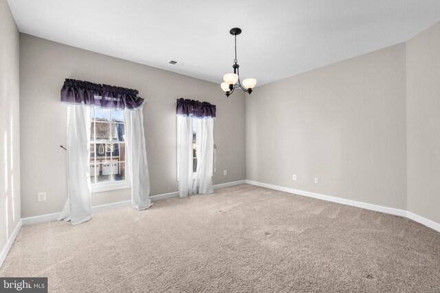 unfurnished room with carpet flooring, a notable chandelier, visible vents, and baseboards