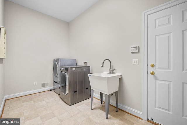 clothes washing area featuring washing machine and dryer, laundry area, visible vents, and baseboards